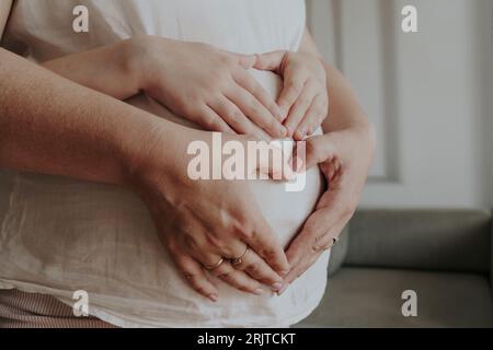 Tochter und Mutter machen Herzform mit der Hand am Bauch Stockfoto