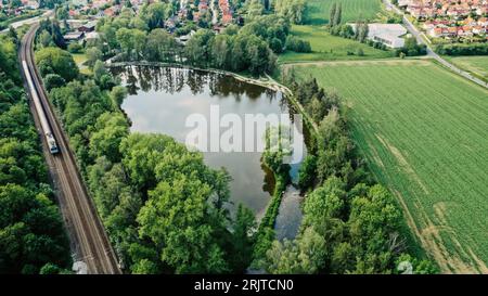 Luftaufnahme einer Eisenbahnstrecke, die sich durch ein dicht besiedeltes Wohngebiet schlängelt, mit zahlreichen Häusern auf beiden Seiten des Flusses Stockfoto