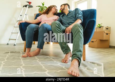 Ein junges Paar sitzt auf dem Sofa in einem neuen Zuhause Stockfoto