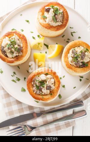 Vol au Vent gebackenes Blätterteig mit Hühnchen, Pilzen und Sahne auf dem Teller auf dem weißen Holztisch. Vertikale Draufsicht von oben Stockfoto