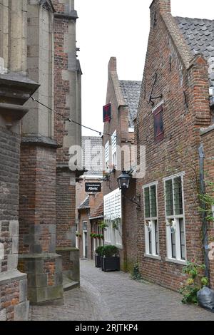 Kirchenmauer, historische Gebäude und enge Straße verleihen dem Sint Stevenskerkhof in Nijmegen ein malerisches Aussehen Stockfoto