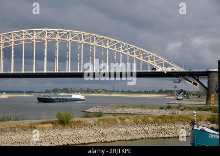 Blick auf die Waal-Brücke. Das Binnenschiff fährt unter der Waal-Brücke, vom Waal-Kai in Nijmegen aus gesehen Stockfoto