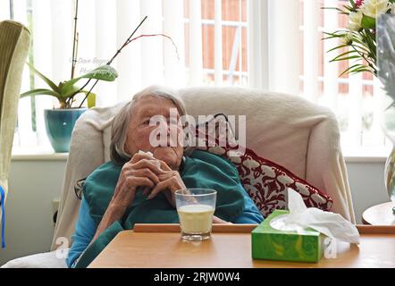 Ältere Dame im Alter von 103 Jahren mit einem Glas Milch und Gewebe in der Hand in Care Home UK Centenarian 100 Jahre alt Stockfoto