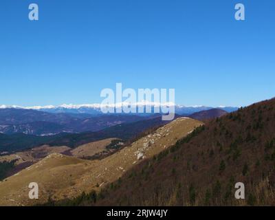 Blick auf schneebedeckte Gipfel der Julischen alpen im Rücken und die Hügel des Trnovo-Waldplateaus und des Nanos-Plateaus davor in Primorska oder der Küstenregion von Stockfoto