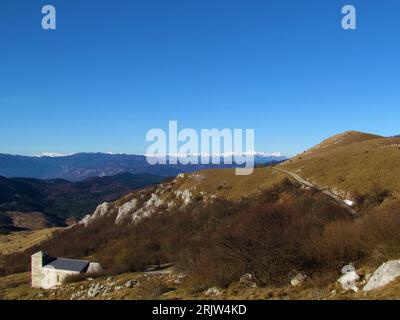 Blick auf das Trnovo-Waldplateau und schneebedeckte Gipfel der Julischen alpen inkl. Triglav aus dem mit Gras und Wald bedeckten Nanos-Plateau in Primorska OR Stockfoto