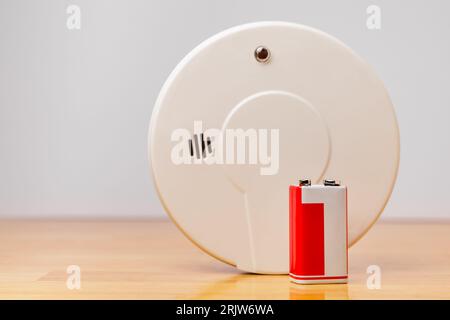 9v alkaline battery with home smoke detector background. Nine volt battery replacement for fire alarm safety. Stock Photo