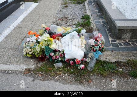 Cemetery waste and garbage. Piled up rubbish left strewn next to graves at the cemetery. Stock Photo