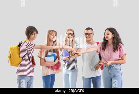 Gruppe von Schülern, die ihre Hände auf hellem Hintergrund zusammenlegen Stockfoto