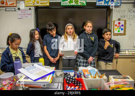 Uniformierte multirassische Schüler einer katholischen Mittelschule in Südkalifornien diskutieren die Bücher, die sie als Gruppe im Klassenzimmer gelesen haben. Stockfoto