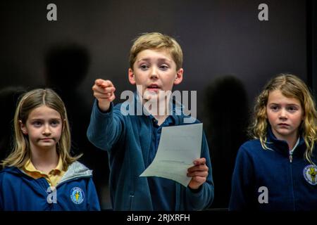 Uniformierte multirassische Schüler einer katholischen Mittelschule in Südkalifornien diskutieren die Bücher, die sie als Gruppe im Klassenzimmer gelesen haben. Stockfoto