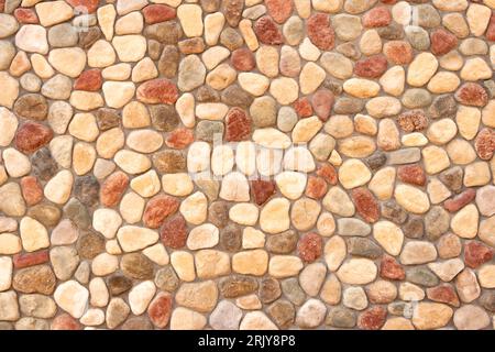 Hochwertiges Bild mit einem nahtlosen Muster aus glatten, bunten Kieselsteinen, die in einem komplexen Mosaikdesign angeordnet sind. Stockfoto