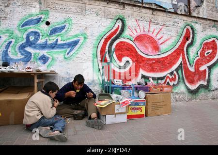 Bildnummer: 52505617 Datum: 09.04.2008 Copyright: imago/Xinhua Palästinenser nehmen einen Imbiss zu sich vor einer Wand mit einem Slogan der Hamas in den Straßen von Gaza Stadt - PUBLICATIONxNOTxINxCHN , Personen; 2008, Gaza, Palästina, Palästinensische Autonomiegebiete, Palästinenser, Israel, Graffiti, Schriftzug; , quer, Kbdig, Gruppenbild, , Gesellschaft Stockfoto