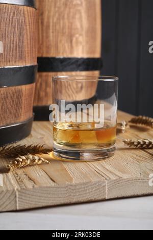 Wooden barrels, glass of tasty whiskey and spikes on white table Stock Photo