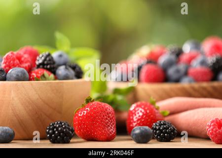 Schüsseln mit verschiedenen frischen Reifen Beeren und Minze auf dem Tisch im Freien, Nahaufnahme Stockfoto