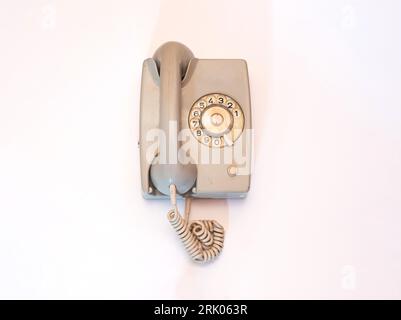 Ein graugrünes Drehtelefon ist auf weißem Hintergrund isoliert. Stockfoto