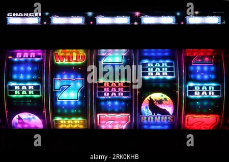 Howling Wolf Illuminated slot machine reels attract players with their colourful graphics and flashing sequences in a darkened amusement arcade. Stock Photo