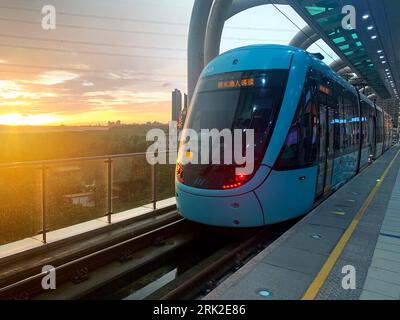 New Taipei City, Taiwan; 2 Jan 2023: A light-rail vehicle to Tamsui Fisherman's Wharf in sunset view. from Hongshulin light rail Station. Stock Photo