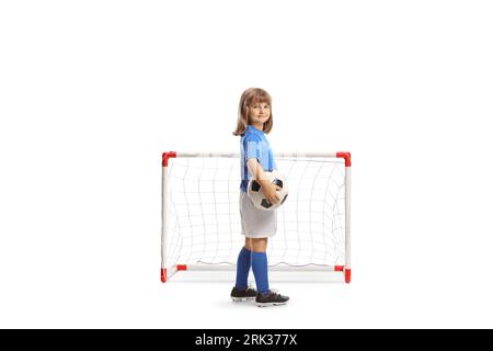 Girl in a football jersey holding a ball in front of a mini goal isolated on white background Stock Photo