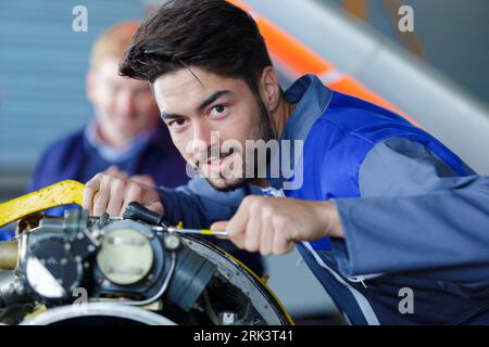Attraktiver junger Mechaniker, der Overalls trägt, der die Kamera betrachtet Stockfoto