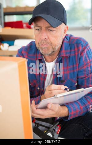 mature man in the workshop making notes on a clipboard Stock Photo