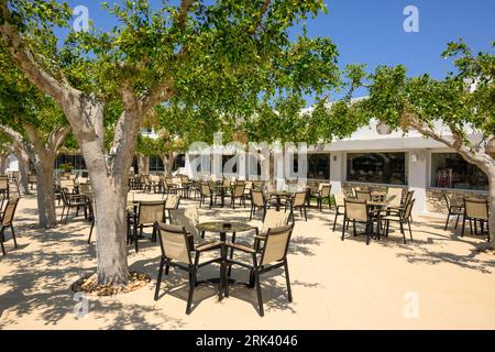 Kos, Greece - May 7, 2023: Cozy Greek hotel cafe terrace with tables and chairs under the trees. Kos Island, Greece Stockfoto