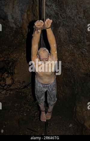 Ein unglücklicher Gefangener hängt an seinen Handgelenken im Kerker von Predjama Castle, Predjamski Grad oder Grad Predjama, einer 800 Jahre alten Festung im Dorf Predjama im Südwesten Sloweniens. Diese uneinnehmbare Festung überstand in den 1400er Jahren erfolgreich eine Belagerung durch einen Habsburgerherrscher, dank Vorräten, die entlang eines Netzes unterirdischer Tunnel in den darunter liegenden Felsen transportiert wurden. Stockfoto