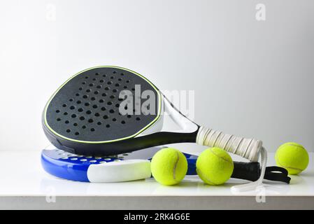 two blue and black paddle rackets on white table with balls and white isolated background. Front view. Stock Photo