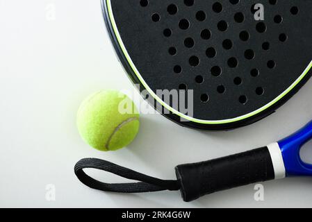 Zwei blaue und schwarze Schläger auf weißem Tisch mit einem Ball. Draufsicht. Stockfoto