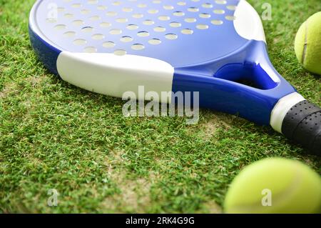 Padel racket and balls on artificial grass floor in outdoor court. Elevated view. Stock Photo