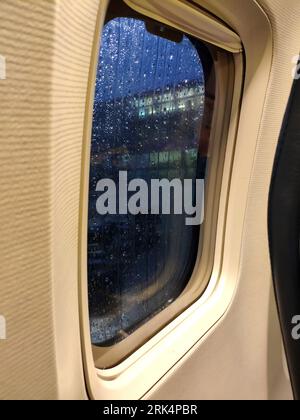 Flugzeugfenster in der Nähe. Regnerisches Wetter vor dem Start Stockfoto