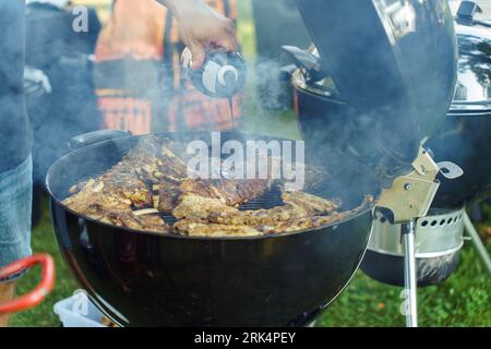 A cook pours sauce over grilled ribs during a barbecue party in the garden in the summer Stock Photo