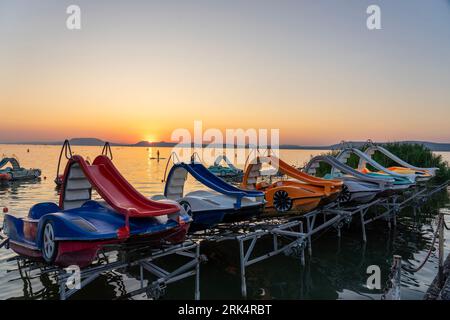 colorful paddle boats funny activity in the sunset with a slide on the lake Balaton in Hungary Stock Photo