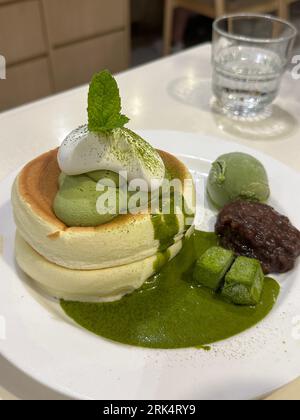 A vertical shot of a plate of freshly cooked pancakes topped with a basil pesto sauce Stock Photo