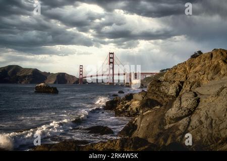 An aerial view of the Golden Gate bridge arcing across a tranquil blue body of water Stock Photo