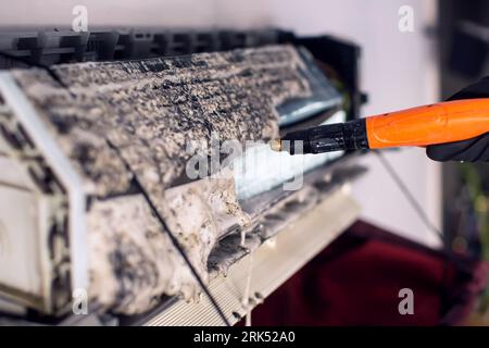 Reinigung der Klimaanlage durch Spritzen. Man wäscht einen speziellen Schaum für die Reinigung der Klimaanlage ab. Das Klimaanlagenkonzept wird beibehalten. Stockfoto