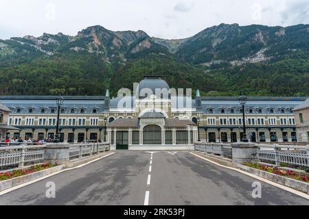 A large contemporary building with white and grey walls situated in a valley surrounded by majestic snow-capped mountains Stockfoto