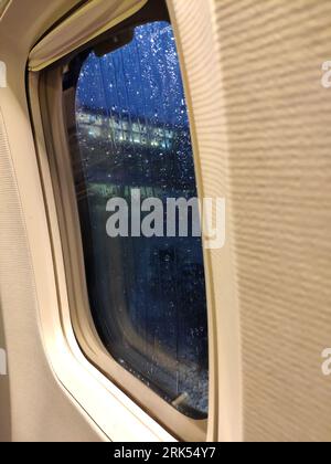 Flugzeugfenster in der Nähe. Regnerisches Wetter vor dem Start Stockfoto