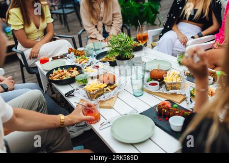 Eine Gruppe von Menschen, die im Sommer gemeinsam in einem Restaurant im Freien essen Stockfoto