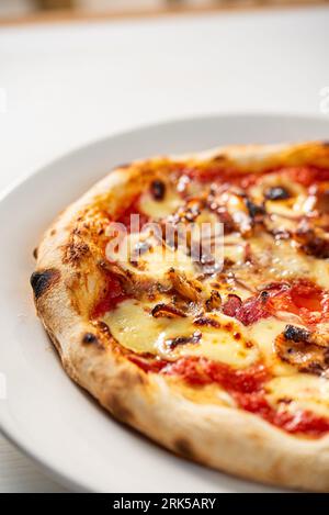 Ein vertikaler Schuss einer köstlichen, frisch zubereiteten Pizza auf dem Tisch Stockfoto