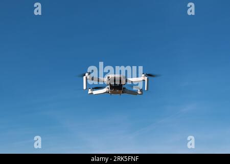 A small black and white drone is seen flying in the air, providing an aerial view of its surroundings Stock Photo