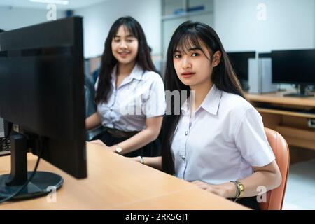 Zwei asiatische Studentinnen sitzen nebeneinander vor einem Computer Stockfoto