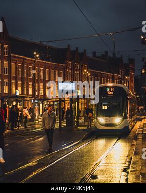 Amsterdam, Niederlande - November 27 2022: An einem kalten, nassen Herbstabend hält eine Straßenbahn vor dem Hauptbahnhof in Amsterdam. Stockfoto