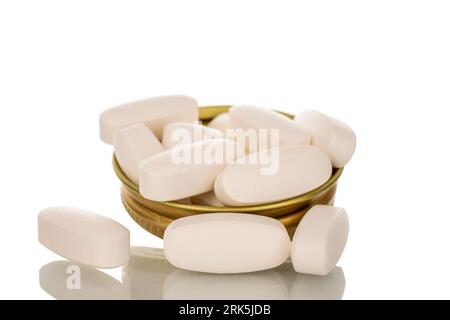 Several medical pills in a metal cap of a glass bottle, macro, isolated on a white background. Stock Photo