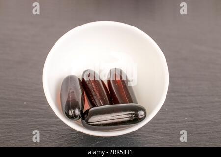 Several medical pills in a ceramic saucer on slate stone, macro. Stock Photo