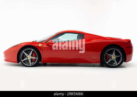 Ein leuchtend roter Ferrari 458 Italia parkte auf einem unberührten weißen Hintergrund Stockfoto