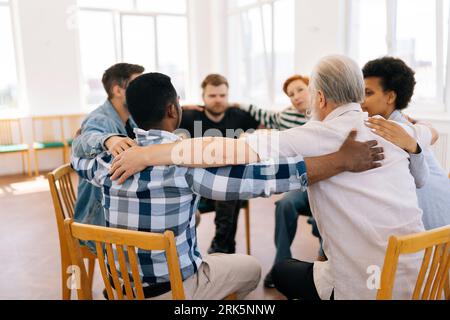 Weitbild einer Gruppe verschiedener Menschen, die während der Gruppentherapie im Kreis reden und sitzen. Multikulturelle Männer und Frauen fühlen sich gegenseitig unterstützt. Stockfoto