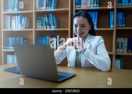 Ein Universitätsprofessor, der einem Studenten der Bibliothek Online-Beratung anbietet Stockfoto