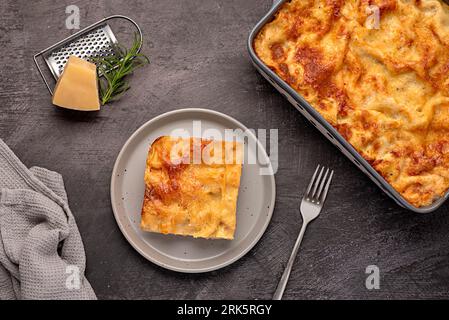 Lebensmittelfotografie von Lasagne; Auflauf; Käse; Tomate; Soße; parmesan; Teller; Handtuch; Ständer; Boden; rustikal; italienisch; Fleisch; mediterrane; Nudeln; frachtbrief Stockfoto