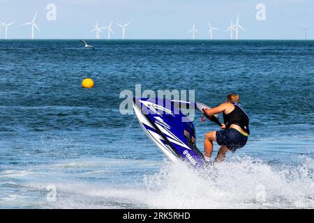 Ein Mann fährt mit dem Jet-Ski über ein ruhiges Gewässer Stockfoto