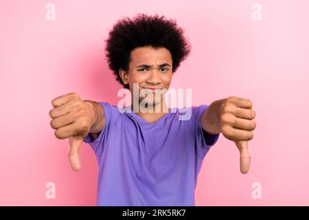 Photo of dissatisfied disappointed gloomy guy wear trendy purple clothes two hands thumbs down bad choice isolated on pink color background Stock Photo